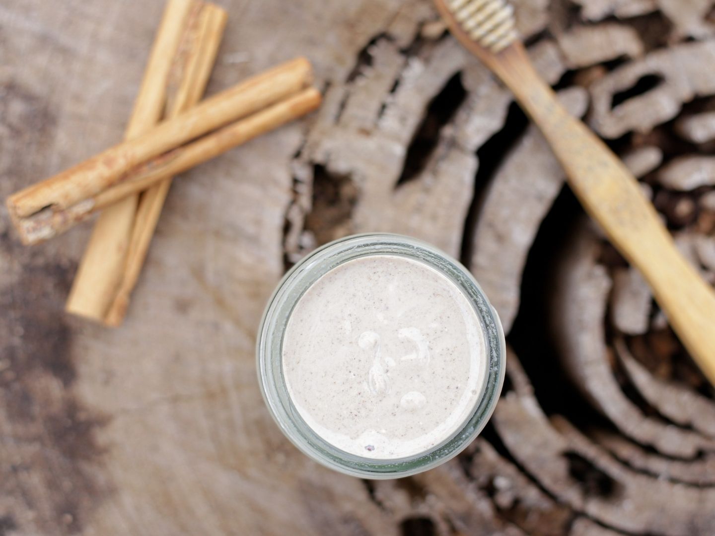 Homemade cinnamon toothpaste with cinnamon sticks and toothbrush in background